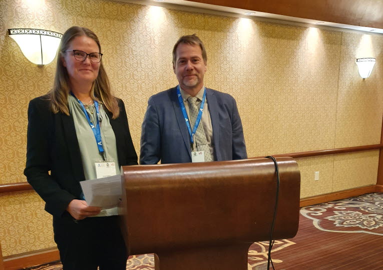 Kvninna och man bakom ett podium i konferenssalen.