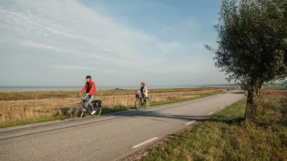 Två personer som cyklar längs en väg.