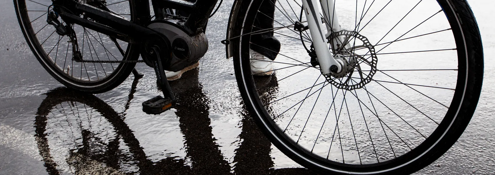 En person som ska cykla på en våt gata.