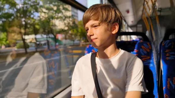 En pojke som sitter på en buss och tittar ut genom fönstret.