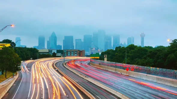 Highway with light effects in the form of lines. Skyscrapes in the background.