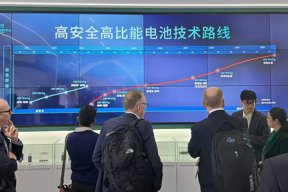 Människor framför stor digital skärm med kinesiska tecken.
